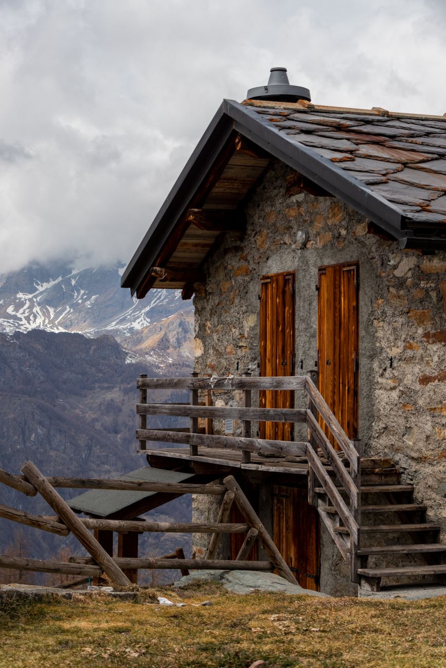 Contemporary wooden and stone cabin set against snowy alpine peaks
